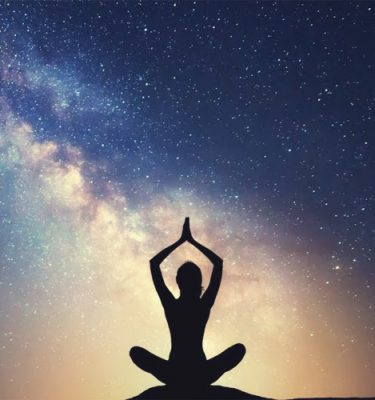 Woman striking a yoga pose among a blue starry night